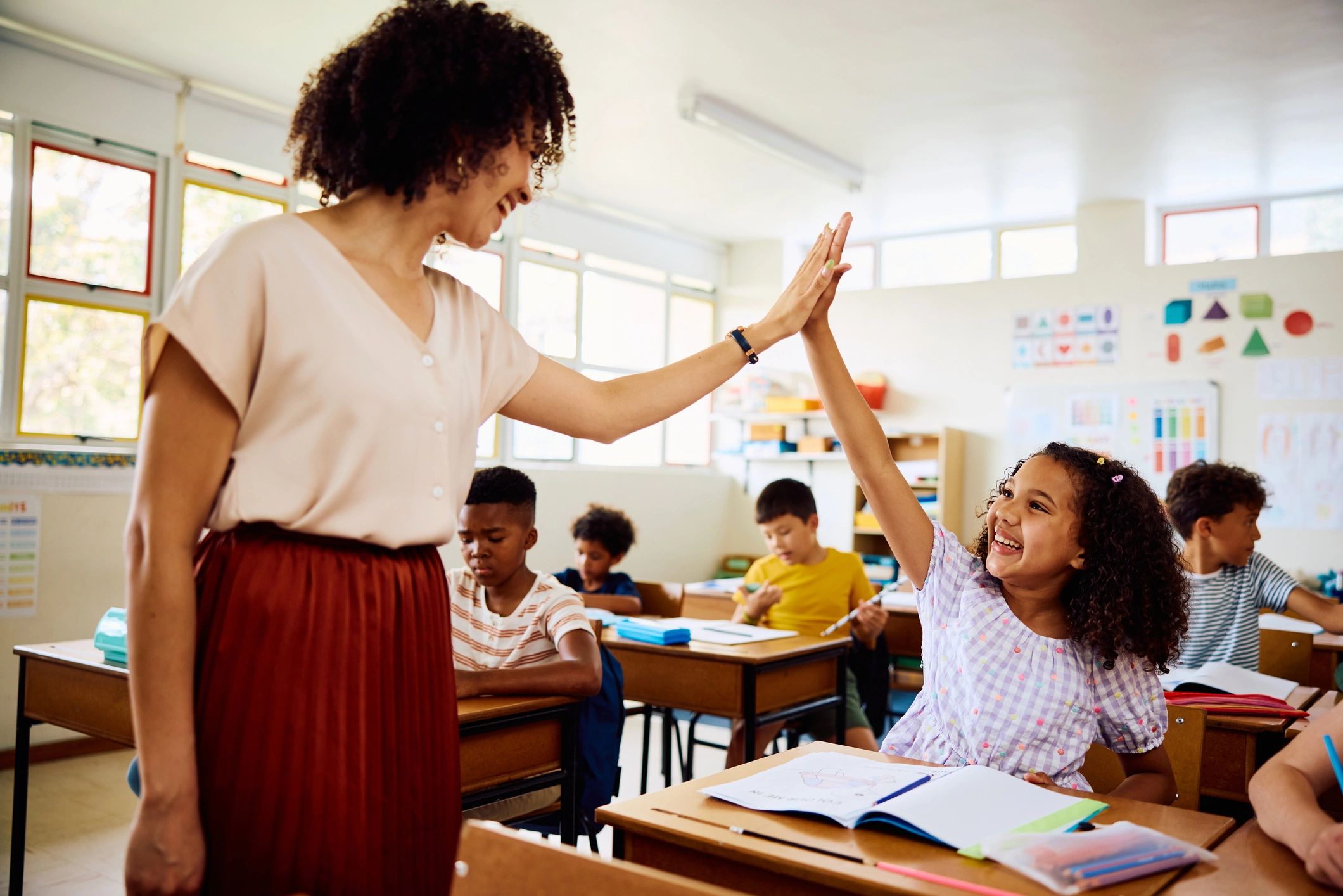 Teacher and children sharing a joyful moment in a bright classroom